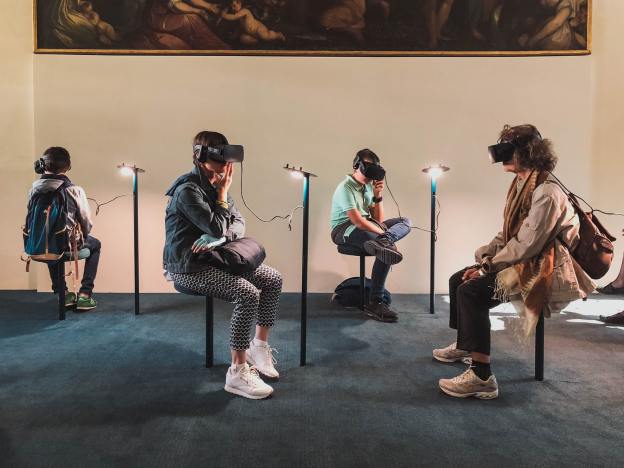 Four people wearing VR headsets sitting in a art gallery.